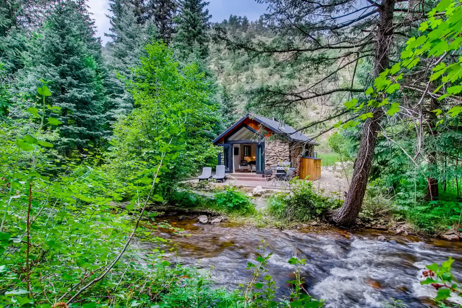 A creekside cabin surrounded by trees at Water & Stone Retreat